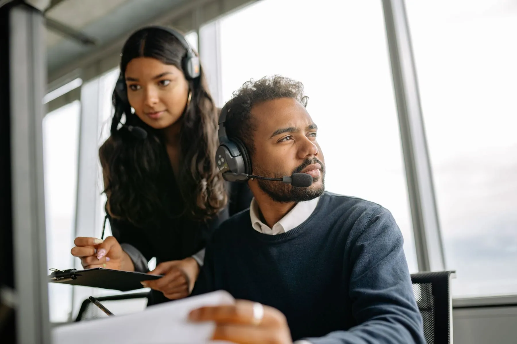 Two support agents with headsets working through a case together at a desk